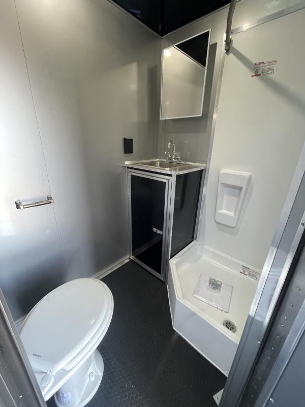 Enclosed Car Hauler 2024 34' Edge Bathroom View. It features a complete bathroom which includes a toilet, corner shower, & sink with vanity.