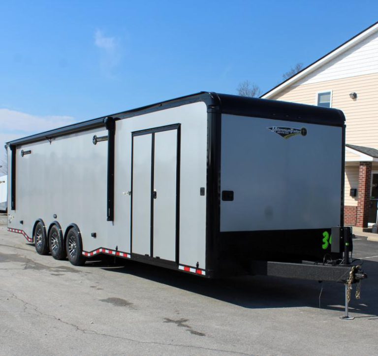 Enclosed Car Hauler 2024 34' Edge Front Curbside View. It features silver bonded exterior with black-out package, electric awning, double side doors, & aluminum wheels.