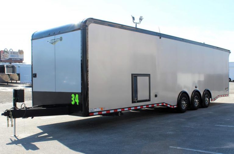 Enclosed Car Hauler 2024 34' Haulmark Edge Front Roadside View. It features an electric tongue jack, stoneguard, silver bonded exterior with black-out package, generator door, & aluminum wheels.