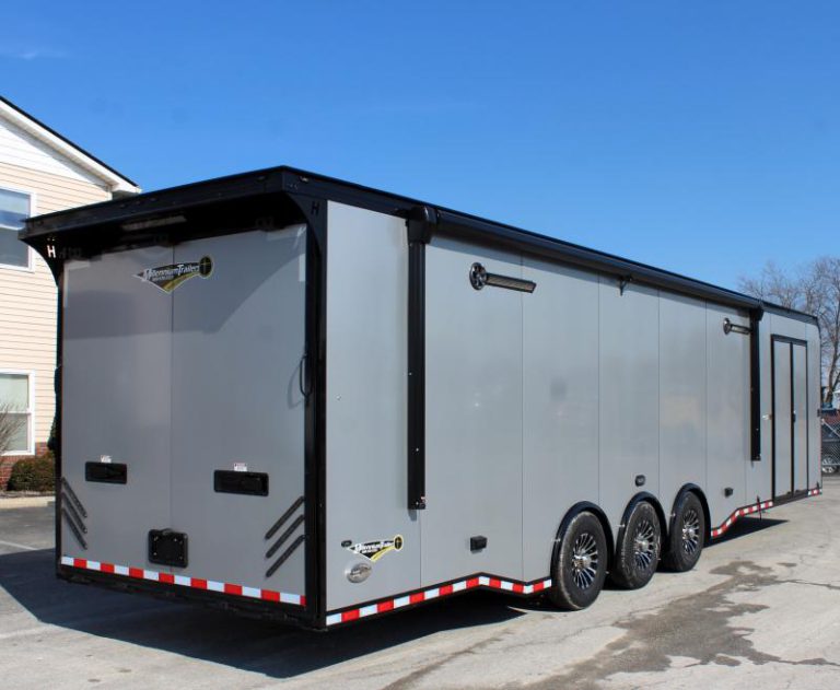 Enclosed Car Hauler 2024 34' Haulmark Edge Rear Curbside View. It features silver bonded exterior, aluminum wheels, electric awning, double side door,speakers, LED lights, rear wing & rear ramp door with recessed latches.