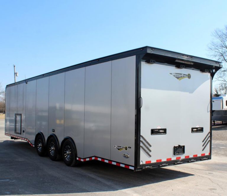 Enclosed Car Hauler 2024 34' Silver Haulmark Edge Rear Roadside View. It features aluminum wheels, bonded exterior with a black-out package, generator door, rear ramp door with recessed latches, and a lighted rear wing.