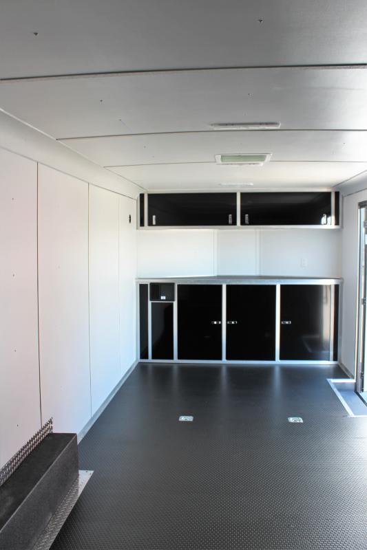 2024 24' Charcoal Heat Interior Front View. The front of the trailer includes black base & overhead cabinets, d-rings, white vinyl walls & ceiling.