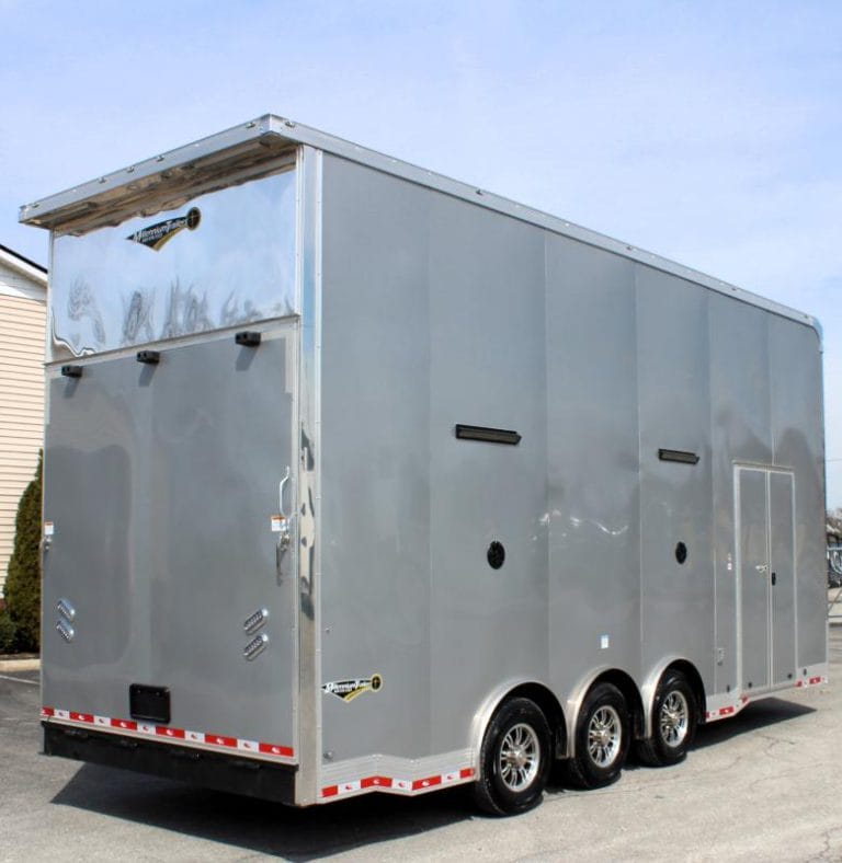 Enclosed Stacker Trailer Rear Curbside View 2024 24' Silver Eliminator. It features the rear ramp door, aluminum wheels, bonded exterior, speakers & L.E.D. lighting.